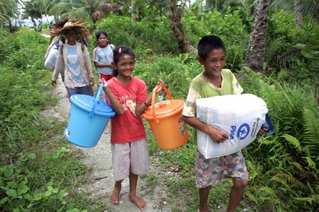 Niños y niñas supervivientes al tsunami en las Islas Metanwai reciben los kits de emergencia distribuidos por Plan International