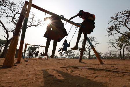 Niños columpiándose en el centro de Cuidado y Desarrollo de la Primera Infancia de Plan International en Uganda