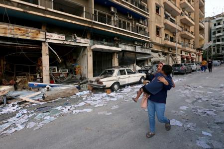 Una mujer corre con un niño tras las explosiones en Beirut Una mujer corre con un niño tras las explosiones en Beirut