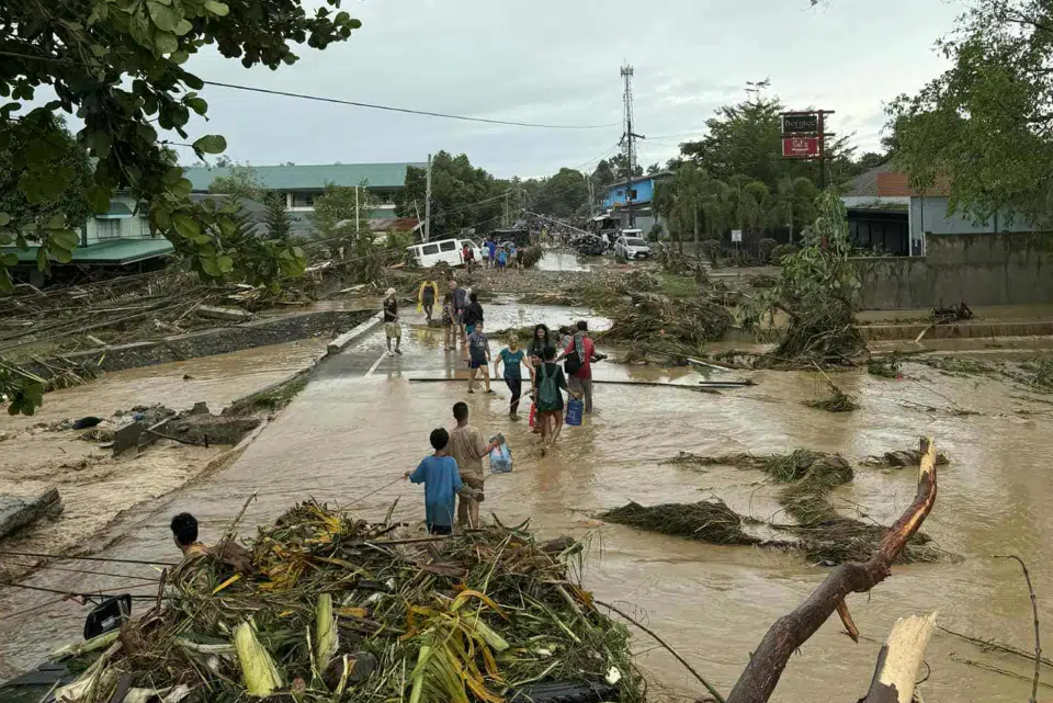 Personas afectadas por los tifones caminan entre el agua y el barro en la provincia de Cebú, Filipinas © Plan International