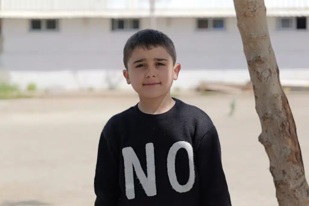 Karim, de 8 años, ha encontrado en el árbol del patio un rincón de refugio de la violencia y el trauma © Plan International / Hasan Noureddine