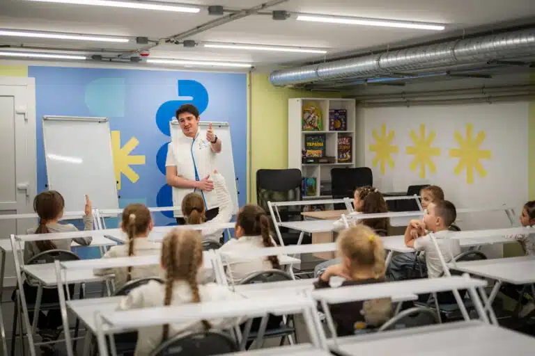 Niños y niñas asisten a clase en uno de los espacios seguros de aprendizaje habilitados por Plan International en comunidades afectadas por la guerra en Ucrania, donde reciben apoyo educativo y psicosocial en un entorno protegido. © Plan International